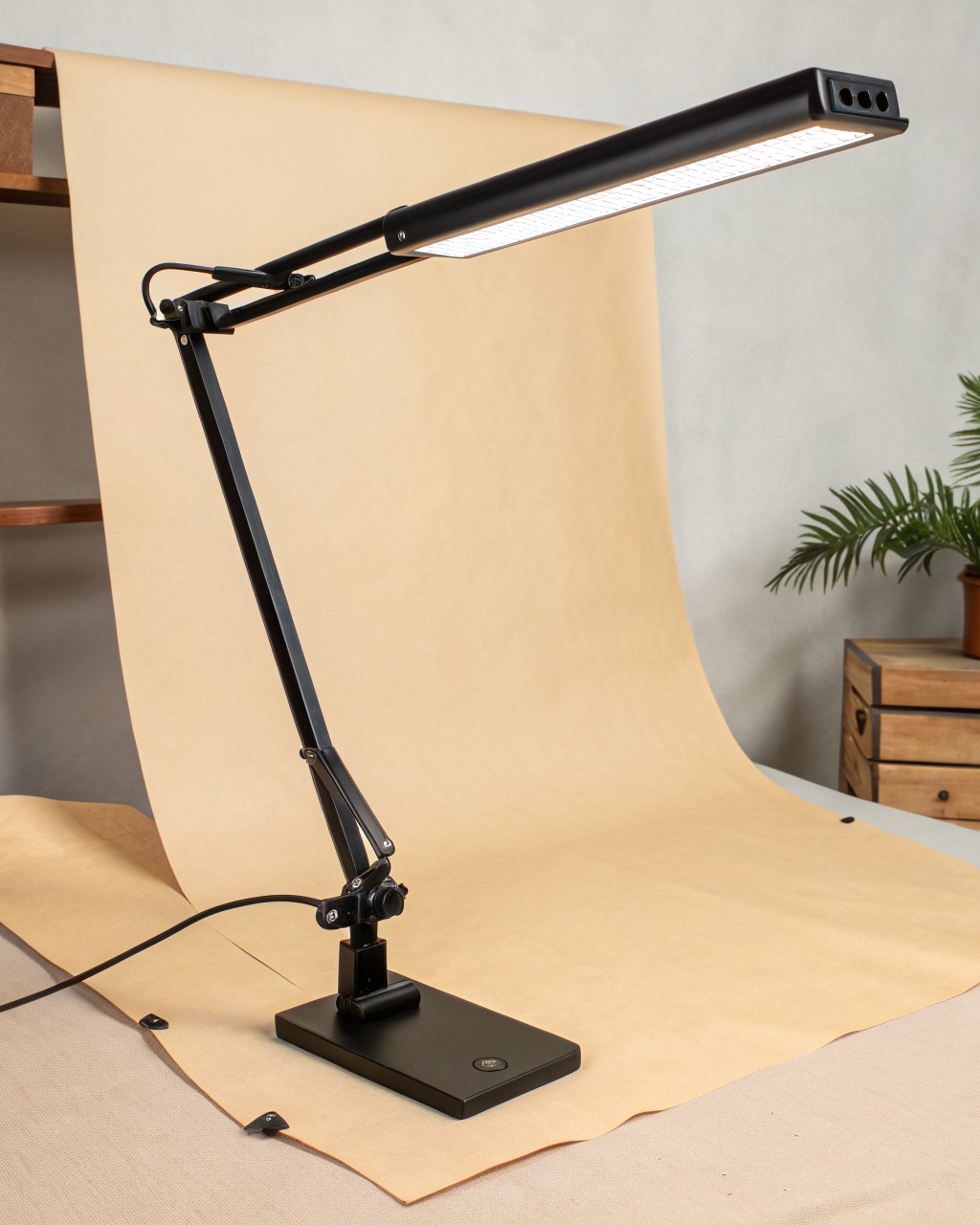 Clamp-mount desk lamp with a wide horizontal LED bar on a matte black articulating arm gripping a desk edge