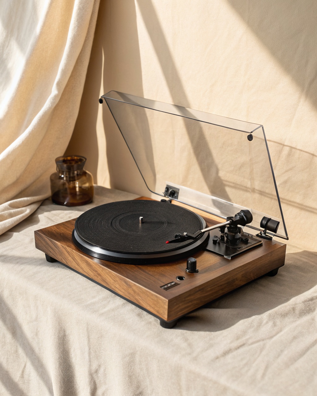 Manual belt-drive turntable with a walnut-veneer plinth, black platter mat, tonearm with counterweight, and a clear hinged dust cover