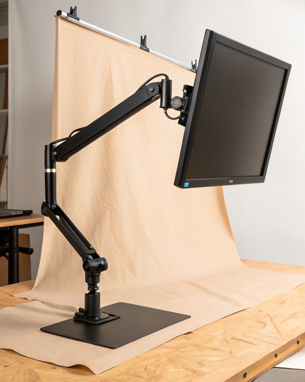 Single-monitor arm in matte black aluminum, holding a monitor at eye level on a desk