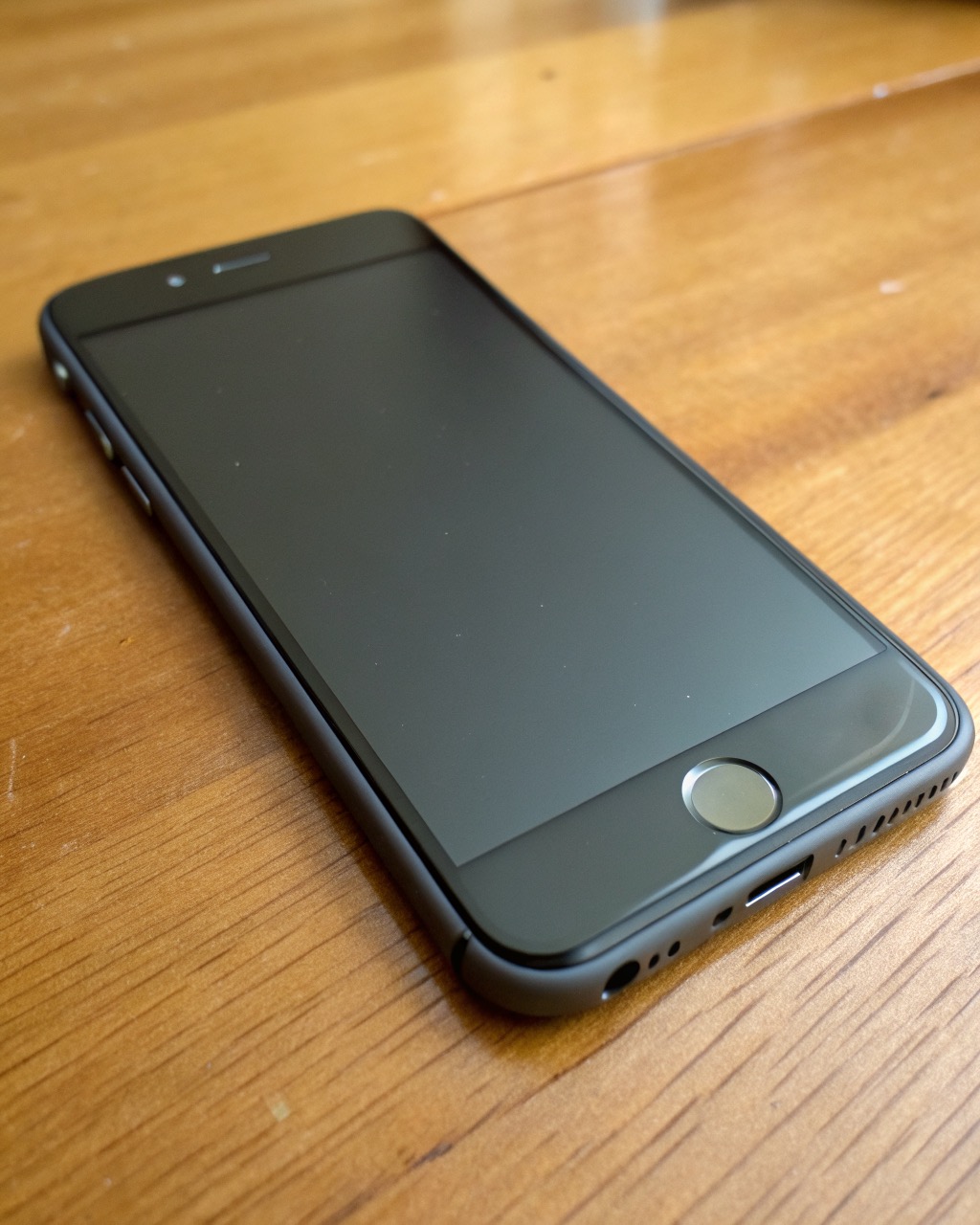 Plain graphite matte smartphone with a small physical privacy switch on the side, dual rear camera, restrained design, blank screen, no branding