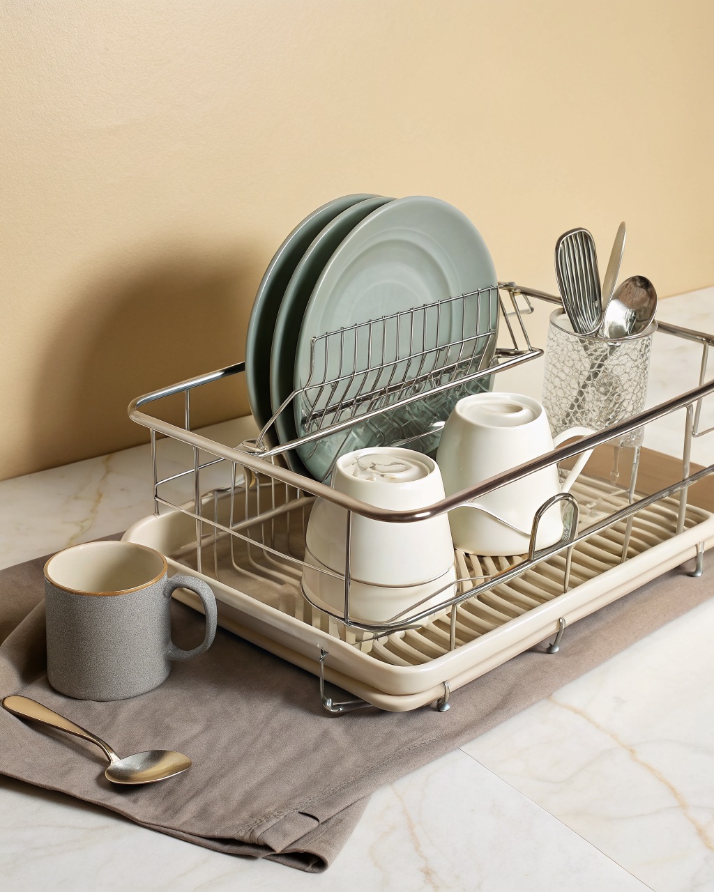 Single-tier stainless steel dish rack holding plates, with a side utensil cup and a grey sloped drainage tray beneath