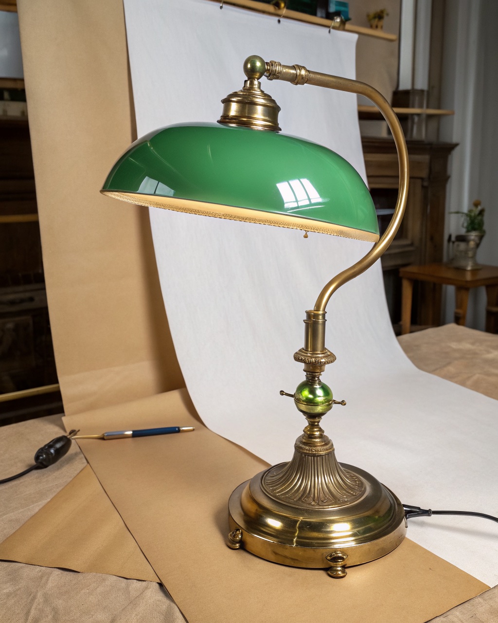 Brass clamp-mount desk lamp with a green opaque glass shade, mounted on a desk edge