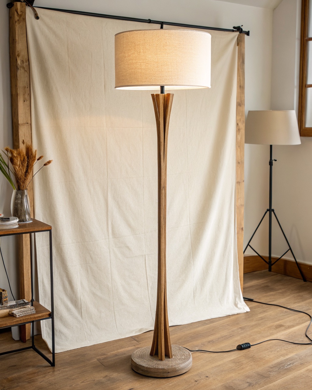 Tripod floor lamp with three oiled solid oak splayed legs joining a steel collar under a tapered cream linen drum shade