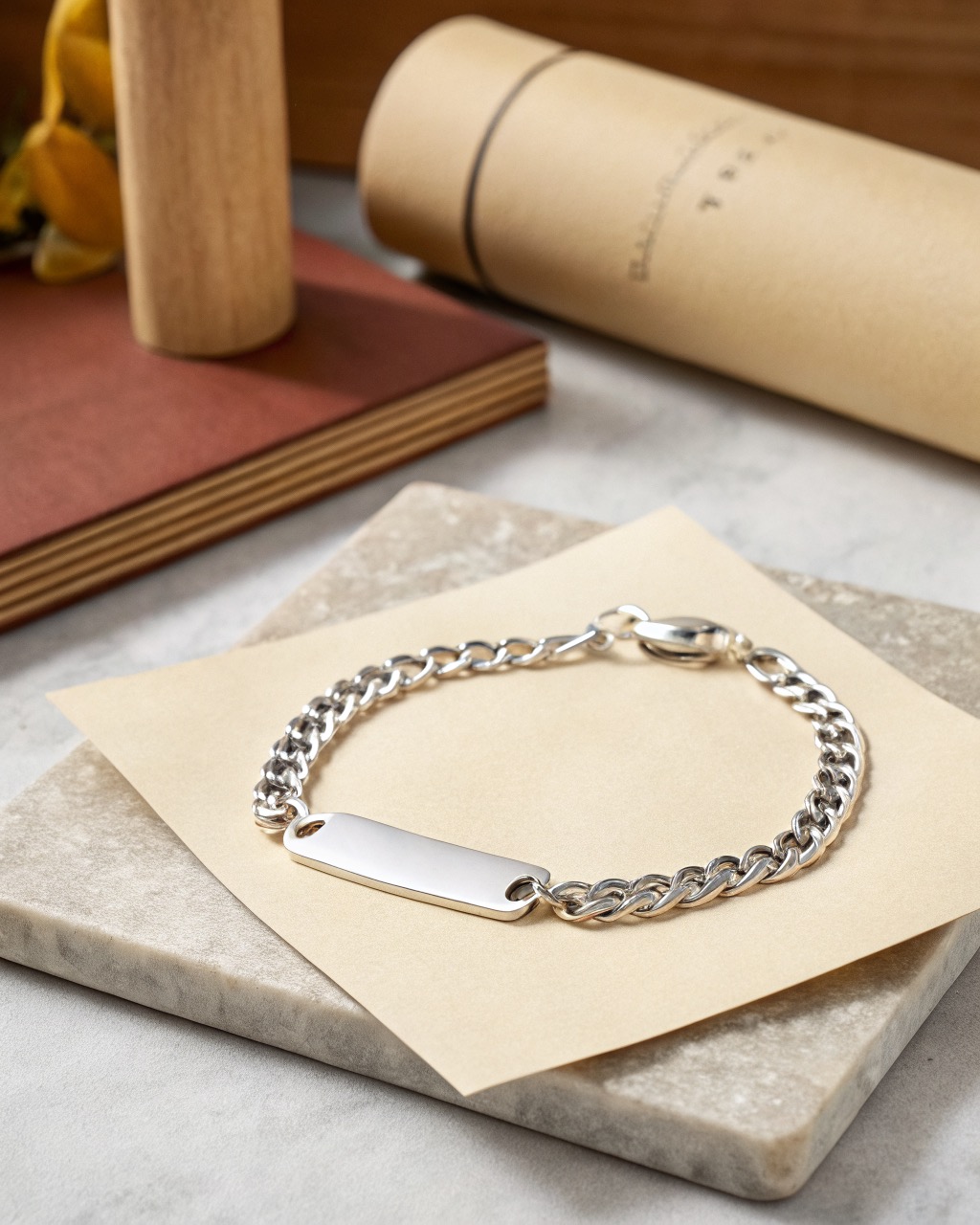 sterling silver ID bracelet with a blank polished plate on a curb chain laid on a pale stone surface, soft reflection on the plate