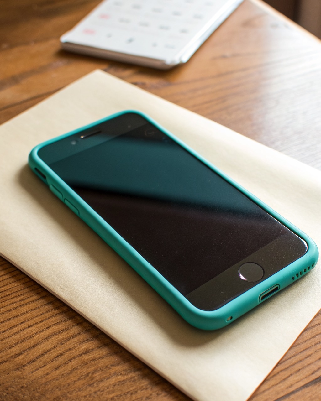 Plain teal plastic smartphone shown front and three-quarter angle, single rear camera, thick bezels, glossy back, no logos or branding of any kind