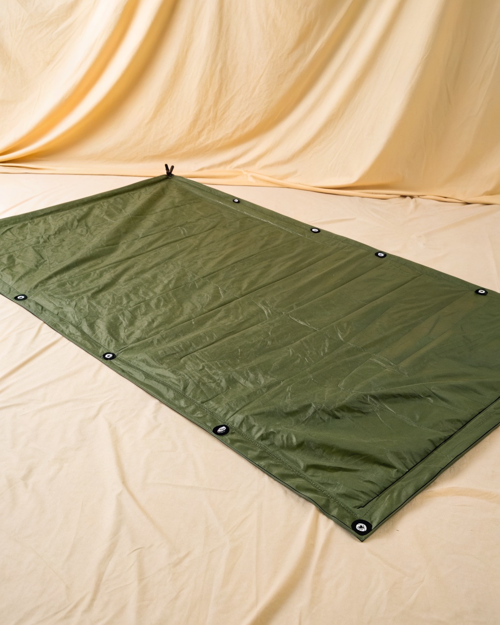 Olive green silicone-coated ripstop nylon ground tarp spread flat outdoors, showing the eight tie-out points