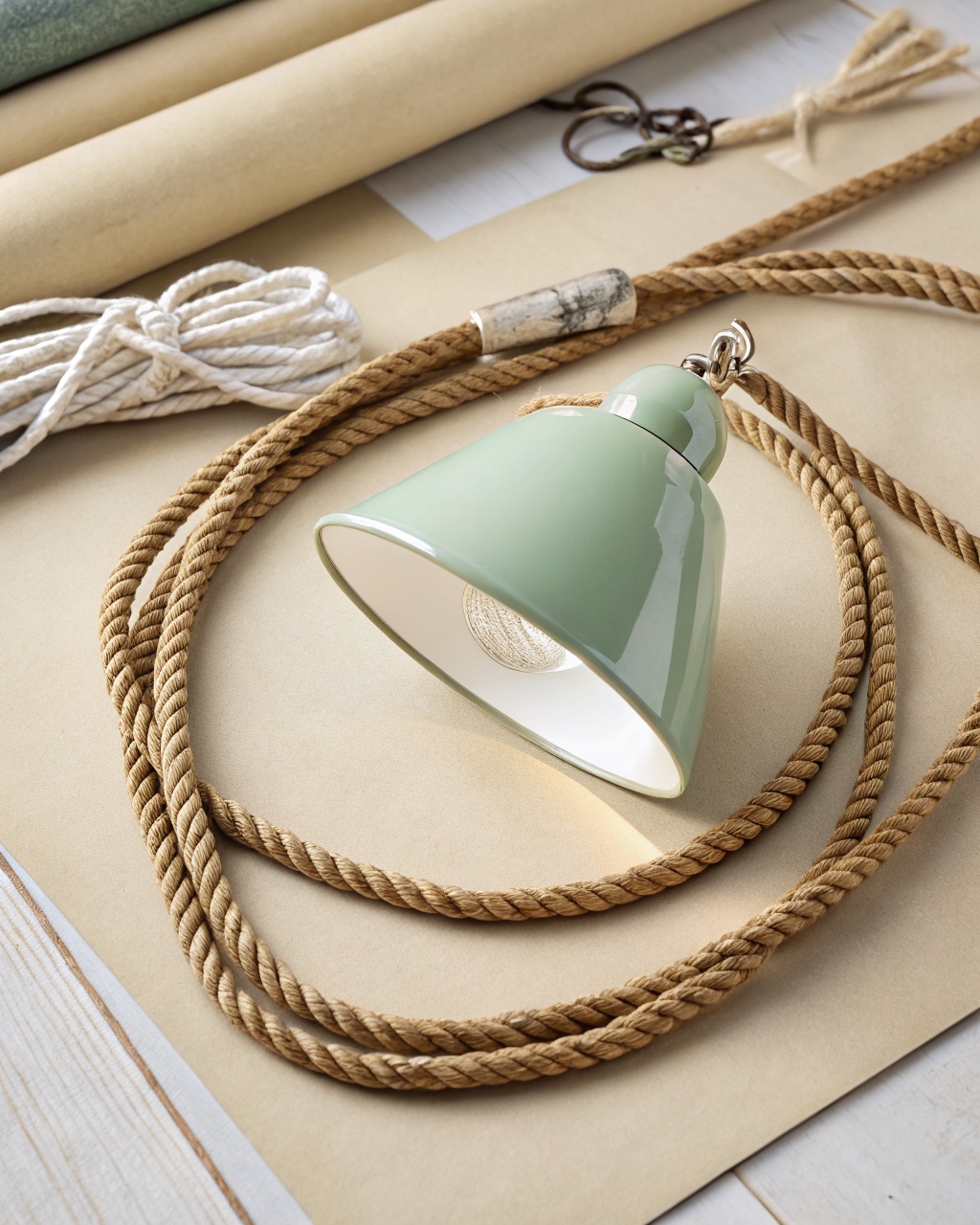 Tapered sage-green spun aluminum pendant shade with a gloss white interior hanging from a woven jute-wrapped cord