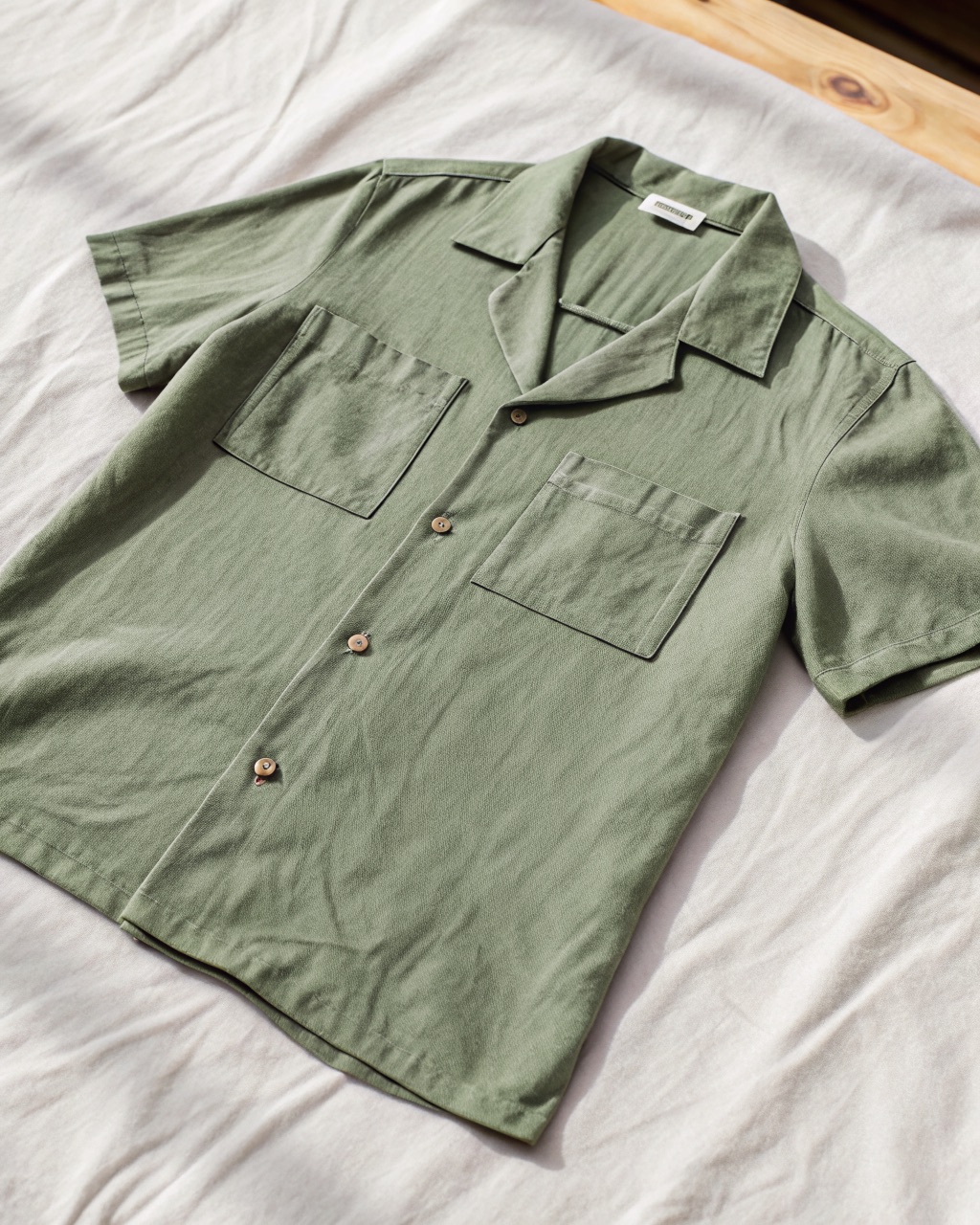 Sage mid-weight linen camp-collar shirt laid flat, showing the open collar, short sleeves, and single chest pocket