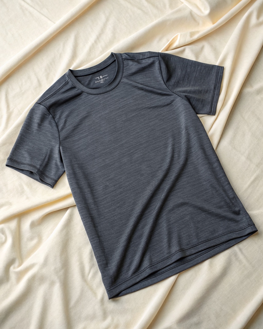 Charcoal merino base-layer tee laid flat showing flatlock seams and a slim short-sleeve cut