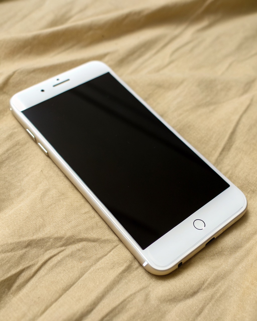 Bone-white smartphone showing a plain grayscale text-only home screen, single rear camera, simple unadorned body, front and angle, no branding