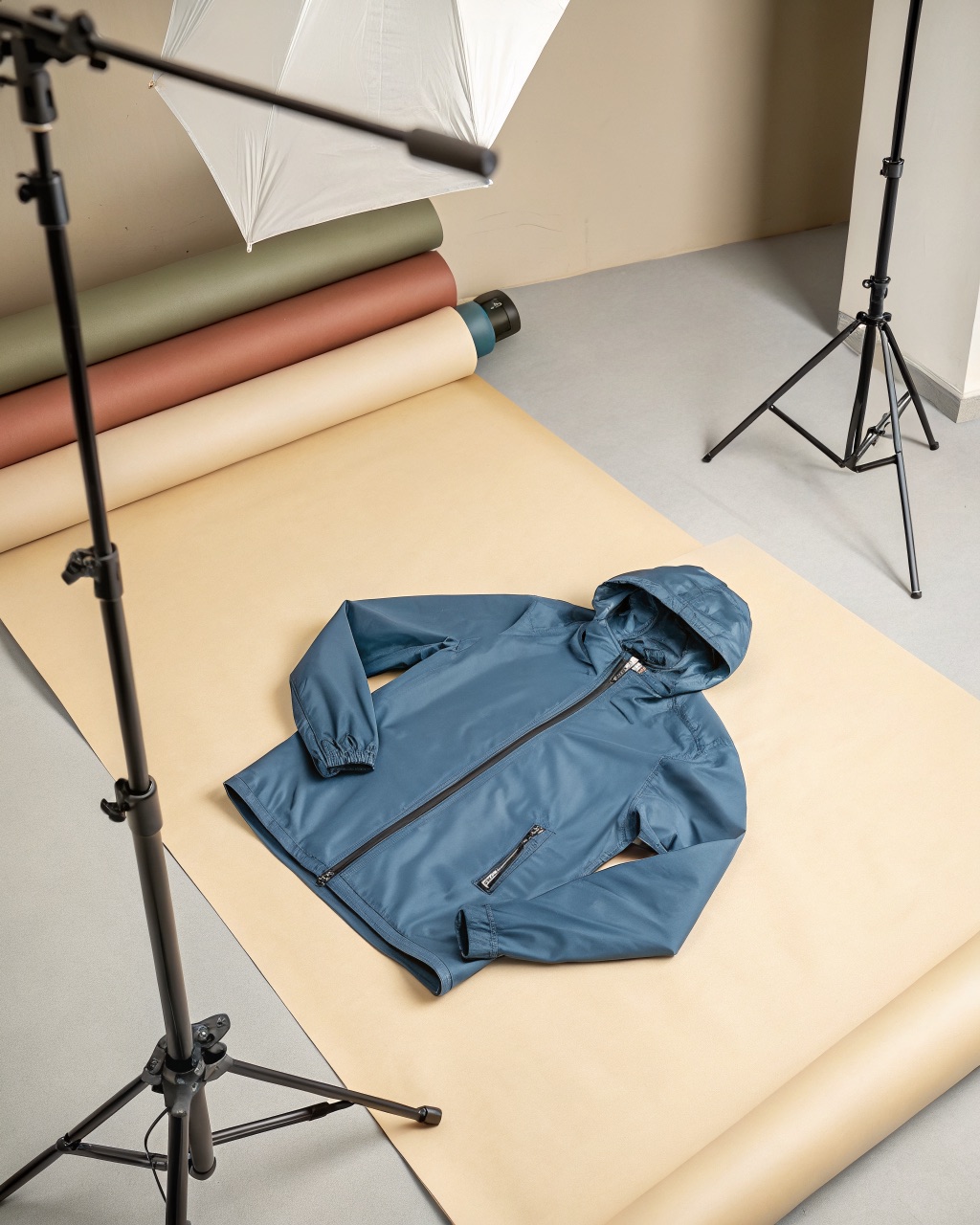 Slate blue packable windshell jacket stuffed into its own chest pocket, compressed to a small bundle