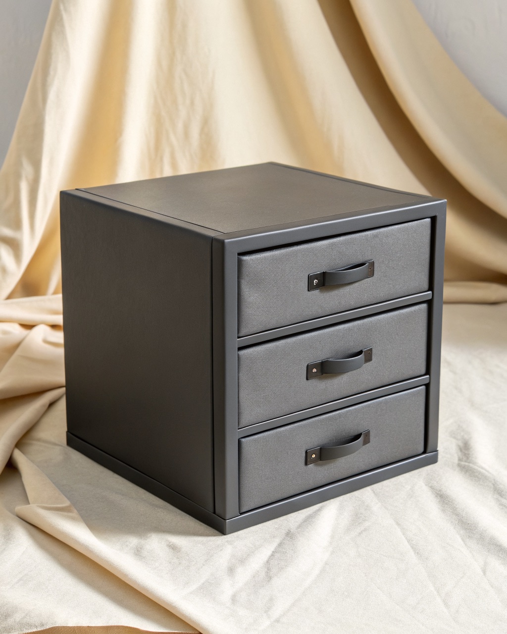 Three-drawer graphite powder-coated steel desktop cabinet with the top drawer open, sitting on a desk
