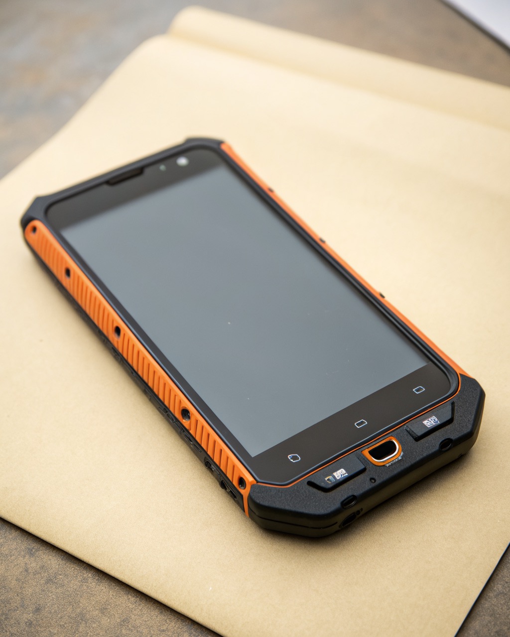 Chunky high-visibility orange and black rugged smartphone with rubberized reinforced corners and exposed bolt detailing, dual rear camera, no logos or branding