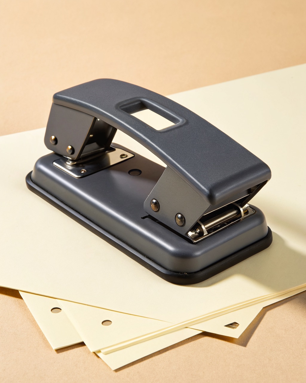 Die-cast metal two-hole paper punch in dark grey with a locking lever and an adjustable paper guide