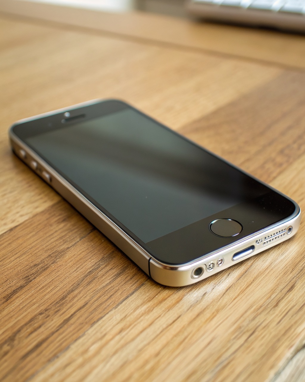 Natural titanium smartphone with a brushed metal frame and flat dark screen, triple rear camera island, three-quarter angle, no branding
