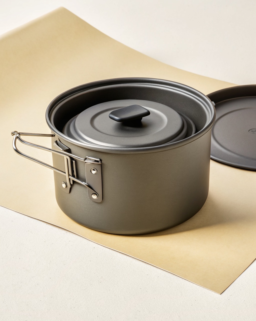 Hard-anodized aluminum trail cook pot with the locking lid partially open, showing the strainer holes