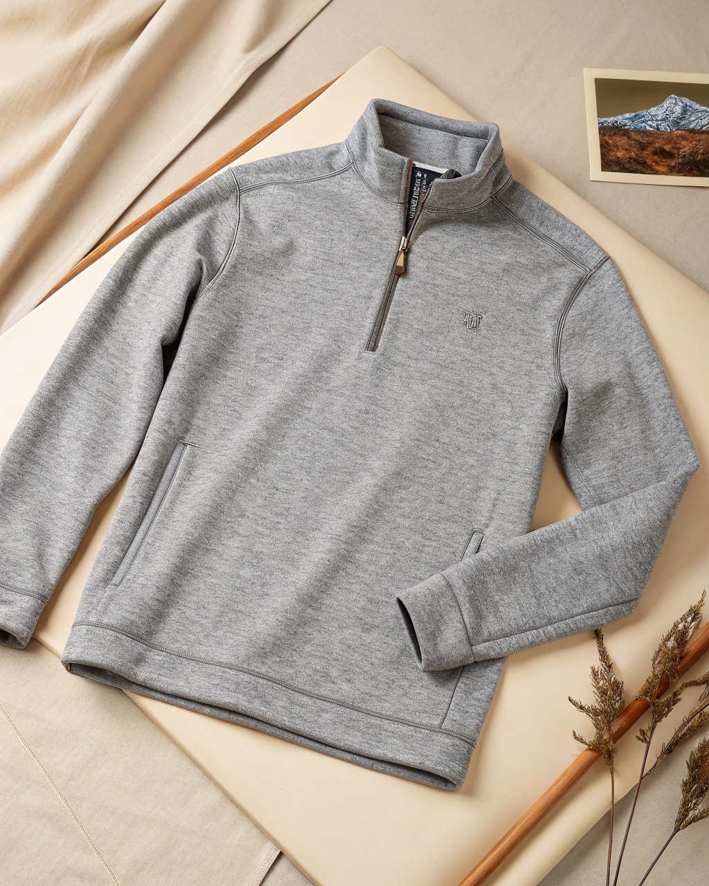 Stone grey quarter-zip fleece pullover on a hanger, showing the smooth exterior and zippered hand pockets